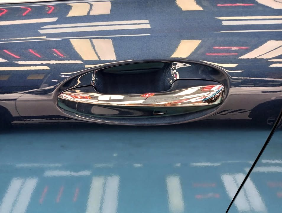 Chrome door handle set into the blue door panel.