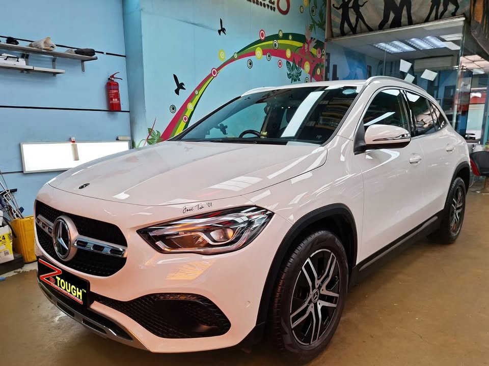 The white Mercedes-Benz GLA 180 from the front three-quarter in the workshop.