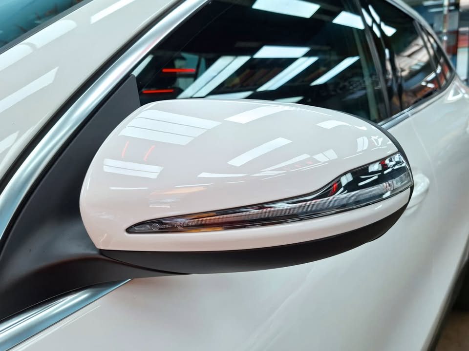 White side mirror of the GLA 180 reflecting the workshop lights.