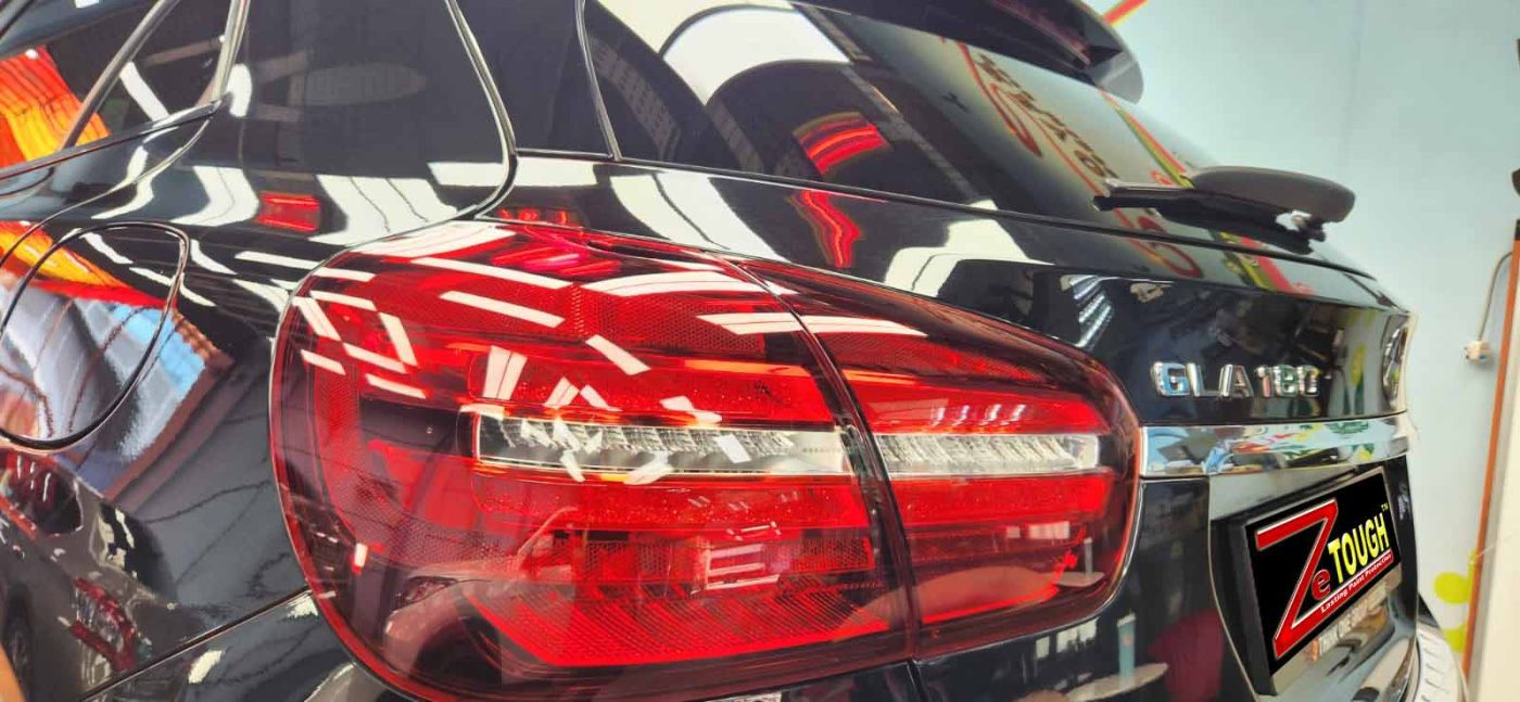 Close-up of a coated body panel reflecting the workshop.