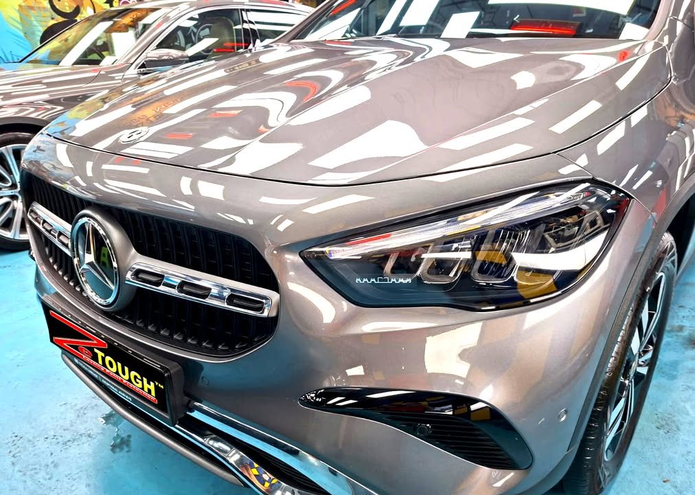 Front of the grey GLA 180 showing the star grille, headlight and bonnet reflections.