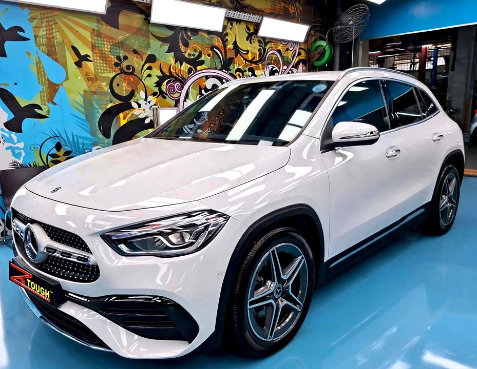 White Mercedes-Benz GLA 200, front three-quarter view in the workshop with a ZeTough plate on the bumper.