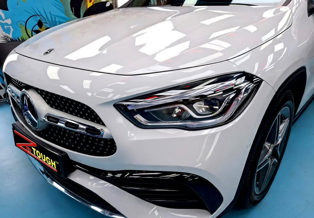 Front of the white GLA 200 showing the grille, headlamp and bonnet reflections.