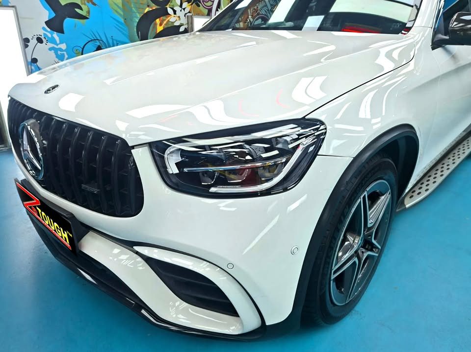 Front of the white GLC showing the vertical-slat grille, headlight and five-spoke wheel.