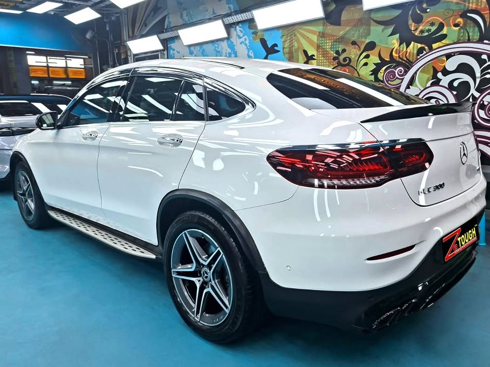 Rear three-quarter view of the white GLC 300 Coupe with boot spoiler and side steps.