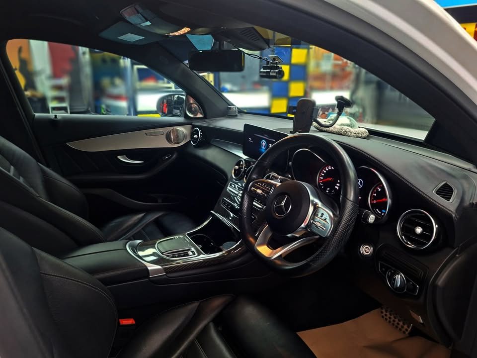 Cabin with black leather seats, steering wheel and wood-trimmed dashboard.