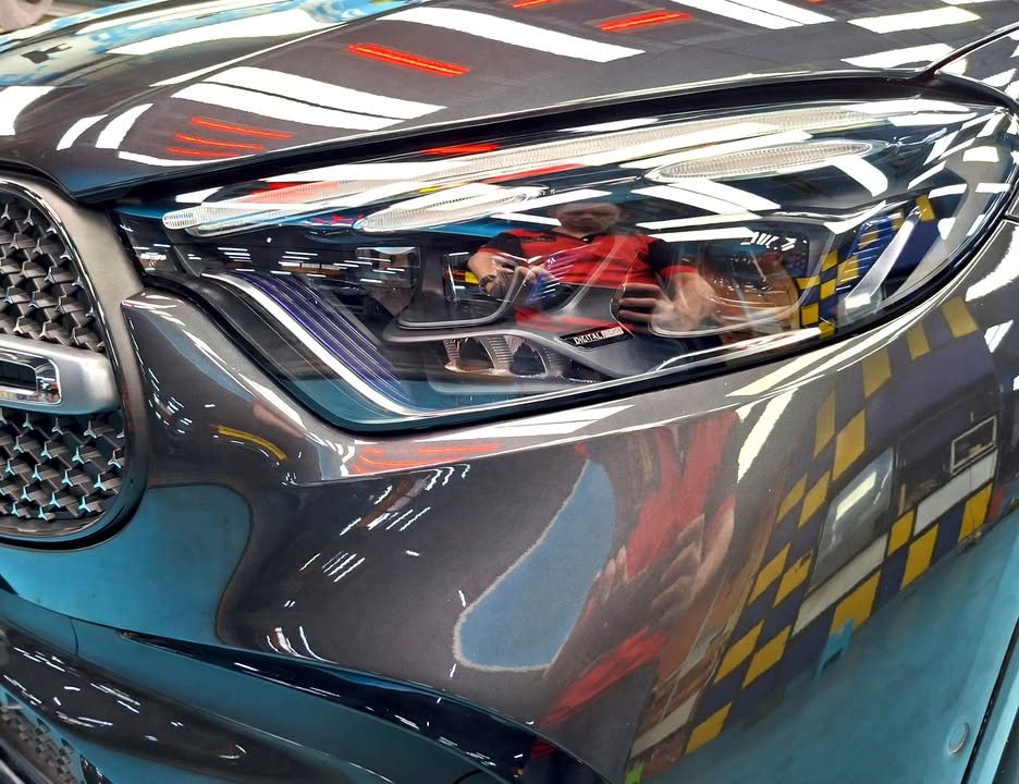 Close-up of the headlight and front wing with sharp reflections in the dark grey paint.