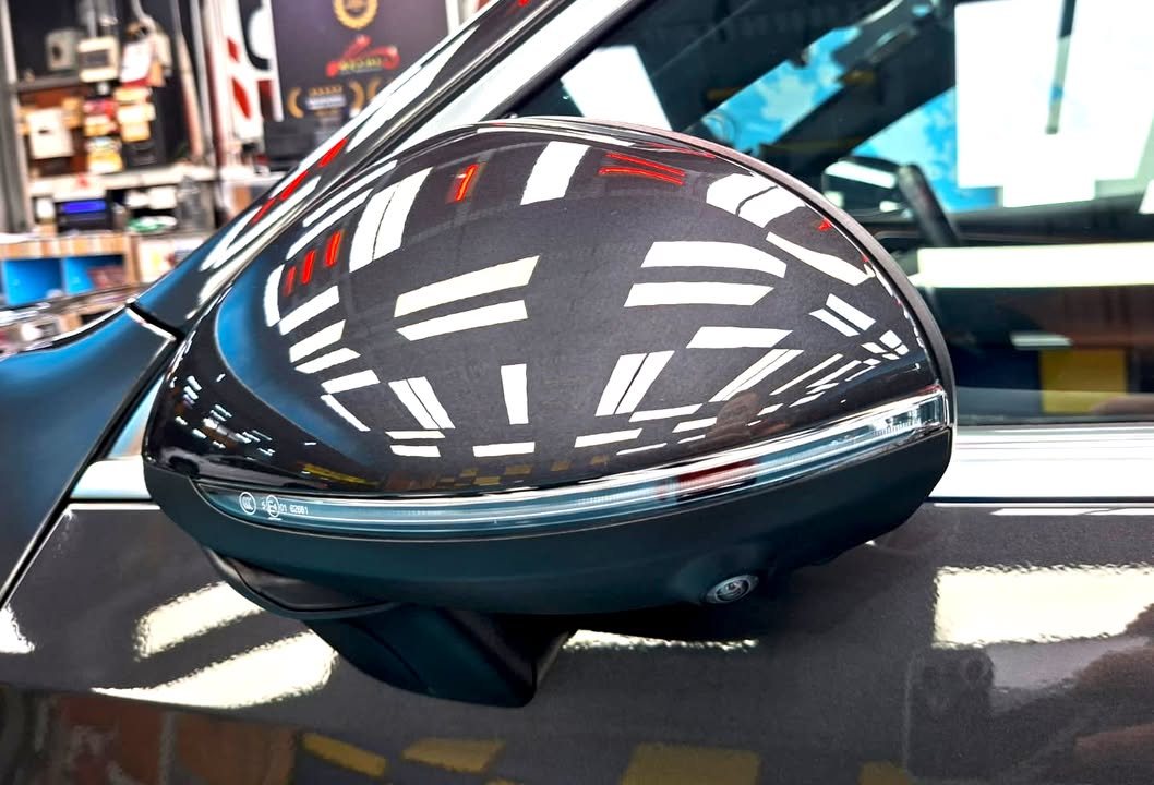 Side mirror cap reflecting the workshop ceiling lights.