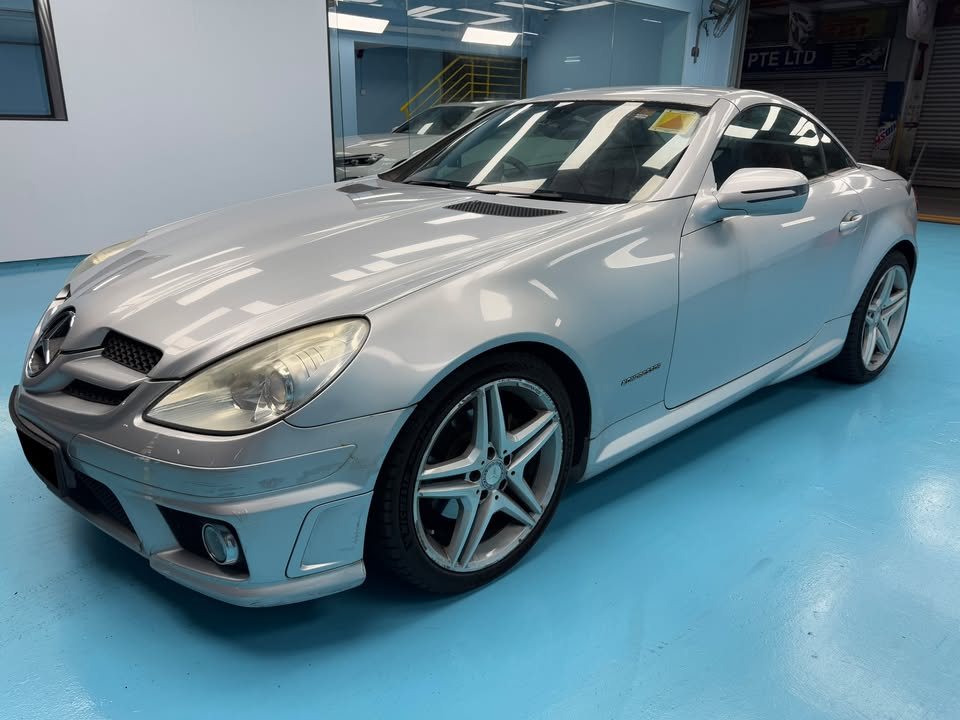Finished silver Mercedes-Benz SLK200 from the front three-quarter on the workshop's blue floor.