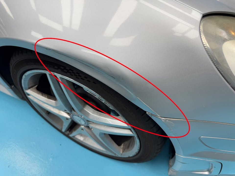 Front wheel arch of the silver SLK200 with damage circled in red before work.
