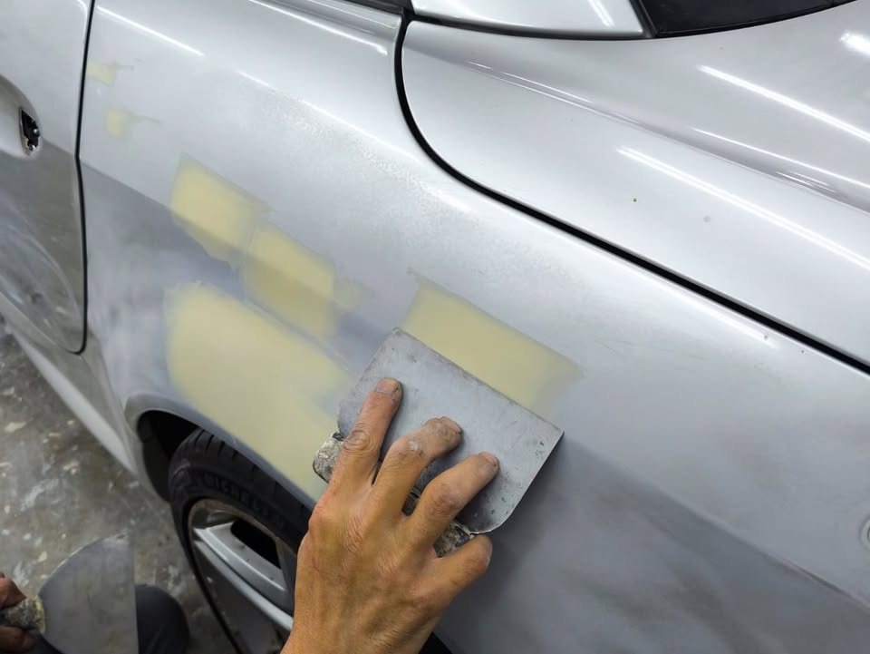 Filler being spread over patched spots on the front wing.