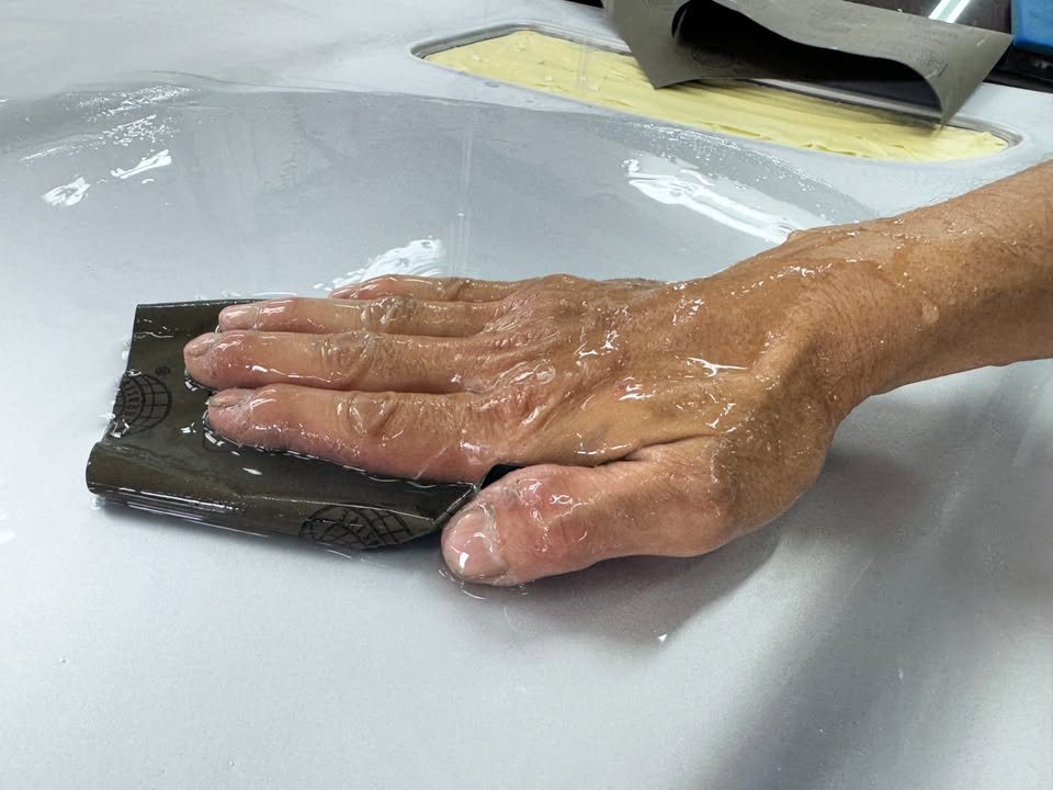 Hand wet-sanding the silver bonnet with a sanding pad.