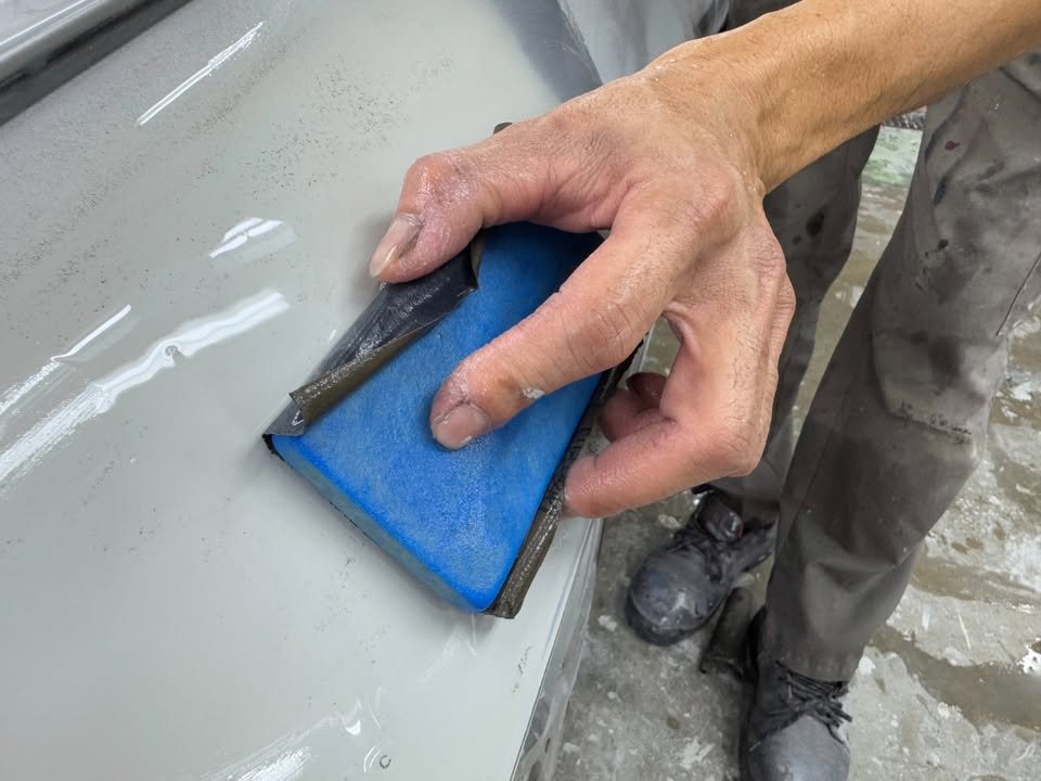 Blue sanding block working the side panel.