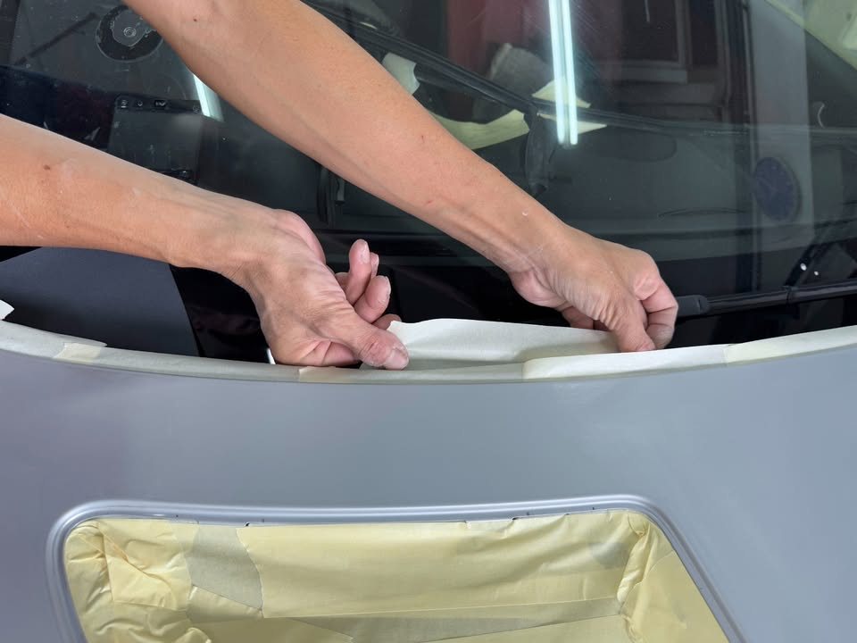 Masking paper and tape being laid around the windscreen.