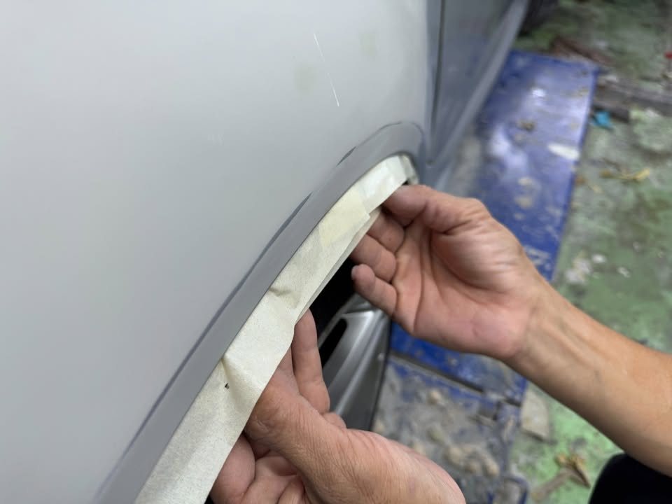 Masking tape being run along the inside of the wheel arch.