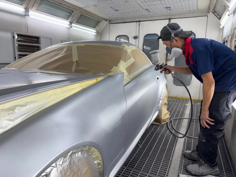 Painter spraying the masked silver SLK200 inside the spray booth.