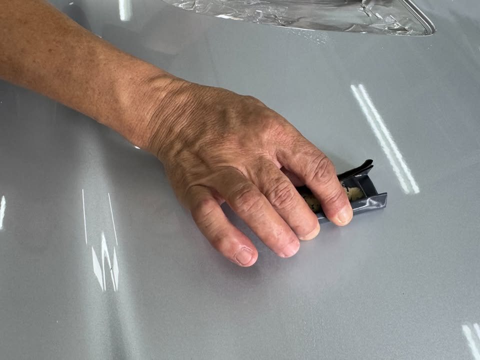 Hand polishing the freshly sprayed silver bonnet.