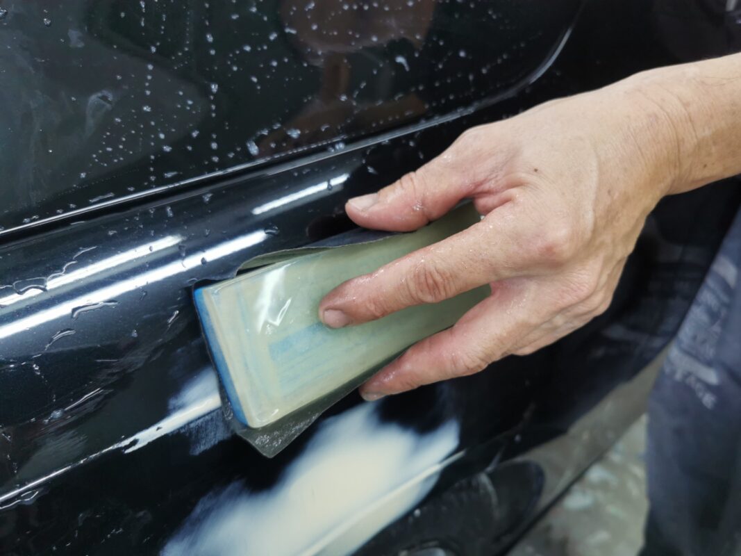 Sanding body filler level on a panel of the Mercedes-Benz CLA180.