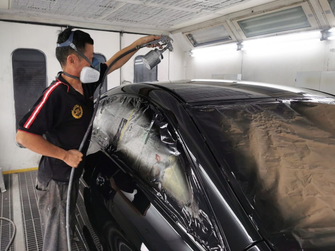 Masking the Mercedes-Benz CLA180's door and glass before the spray booth.