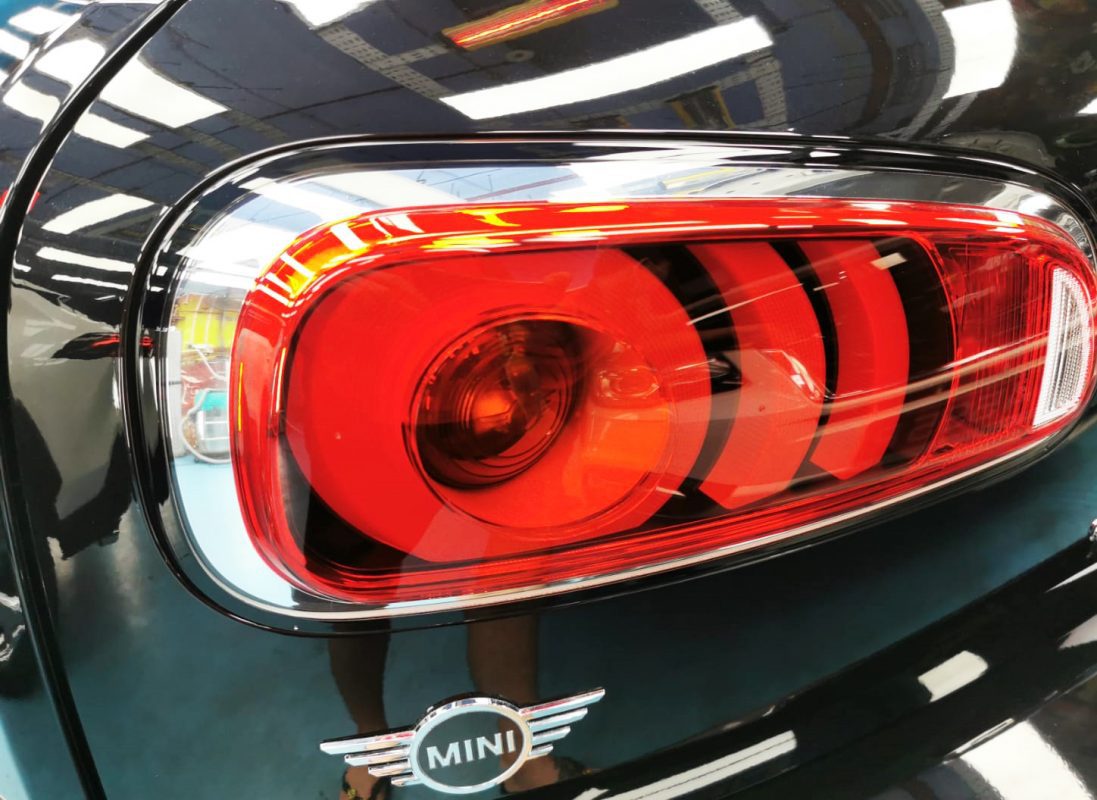 The coated bonnet of the Cooper under workshop lighting.