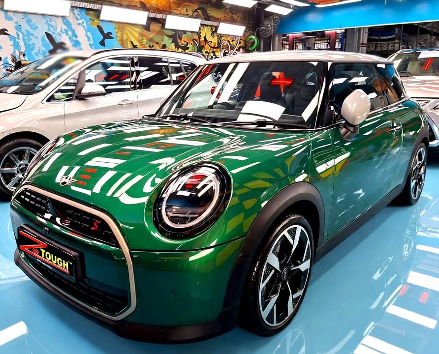 Green MINI Cooper with a white roof, front three-quarter view in the workshop after ZeTough Titanium coating.