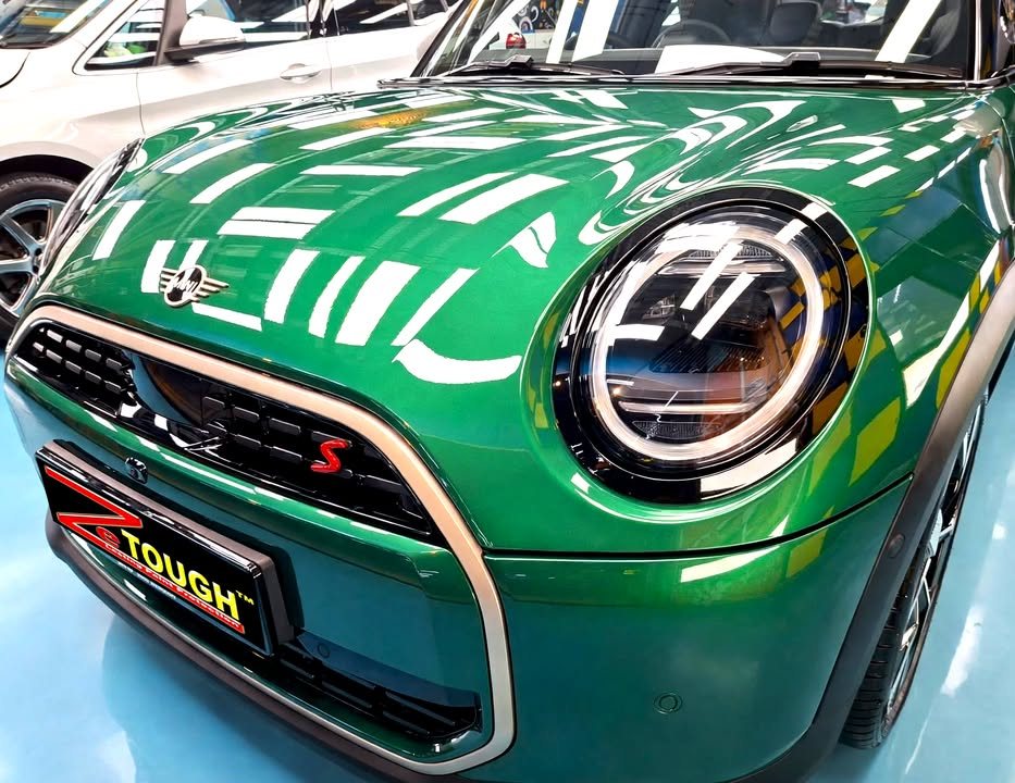 Front of the green MINI Cooper showing the round headlamp, grille and ZeTough plate.