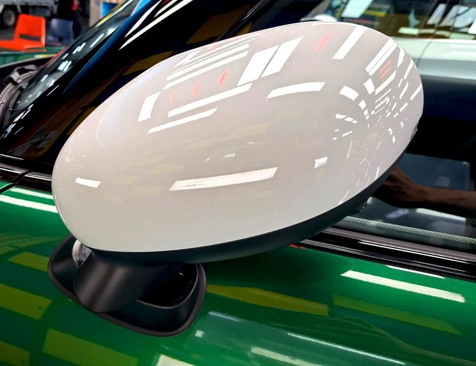 White mirror cap on the green MINI Cooper with a glossy finish.