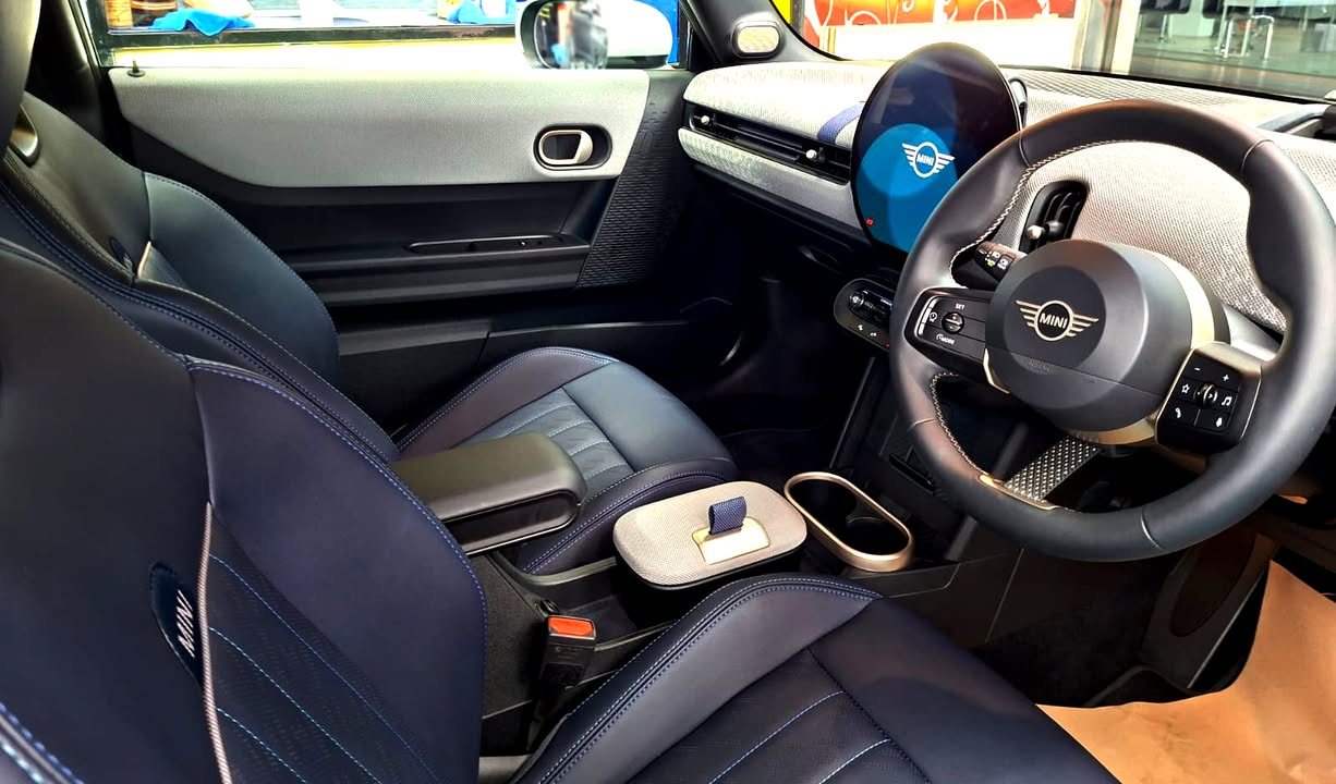 Front cabin of the MINI Cooper with dark seats and the round central display.