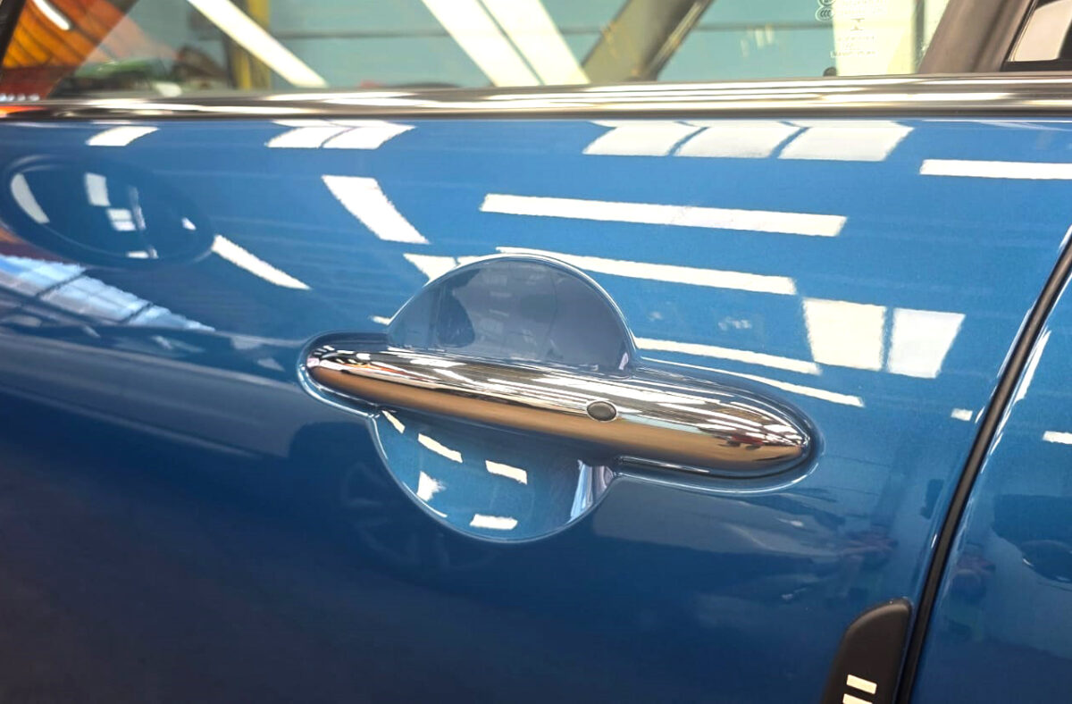 The coated bonnet of the MINI One under workshop lighting.