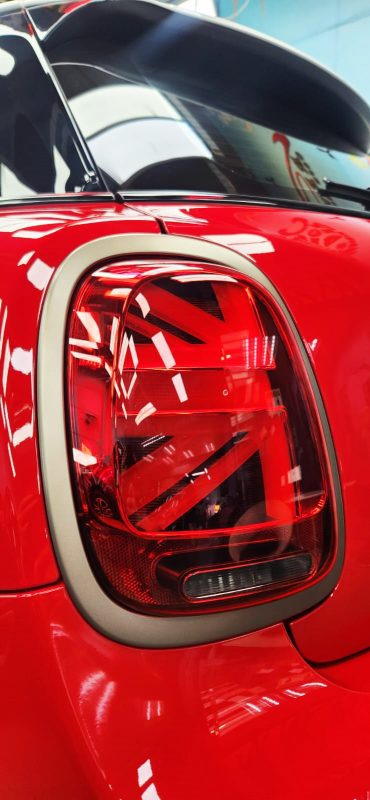 The coated bonnet of the MINI One under workshop lighting.