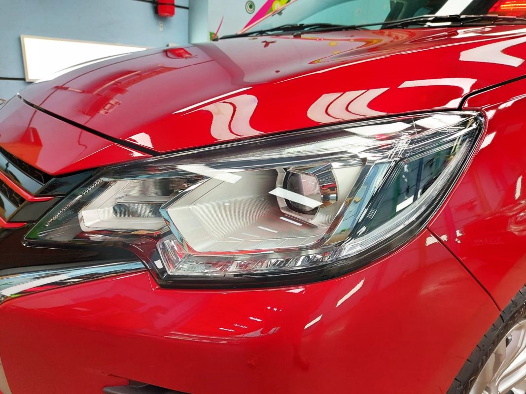 The Attrage's coated red paintwork showing clean reflections.