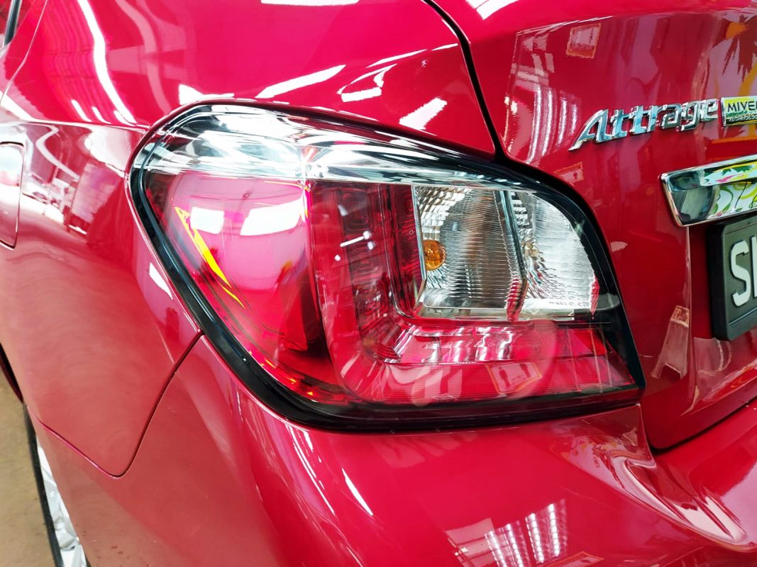 The coated bonnet of the Mitsubishi Attrage under workshop lighting.