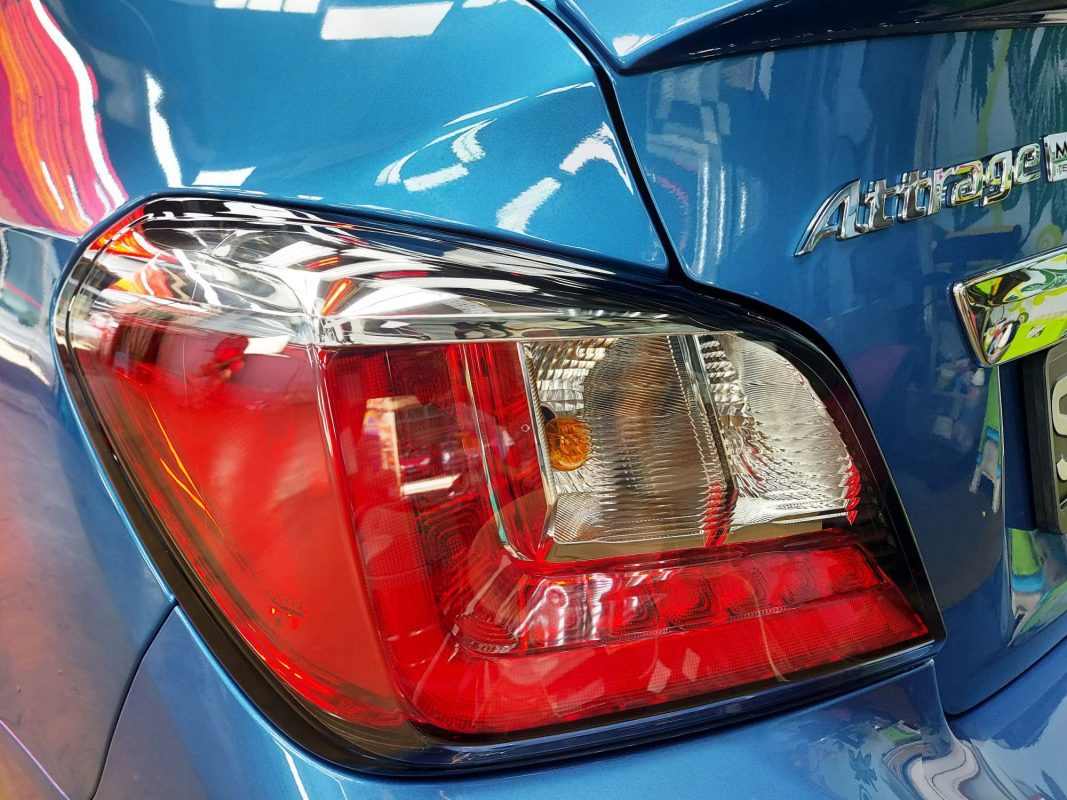 The coated bonnet of the Mitsubishi Attrage under workshop lighting.