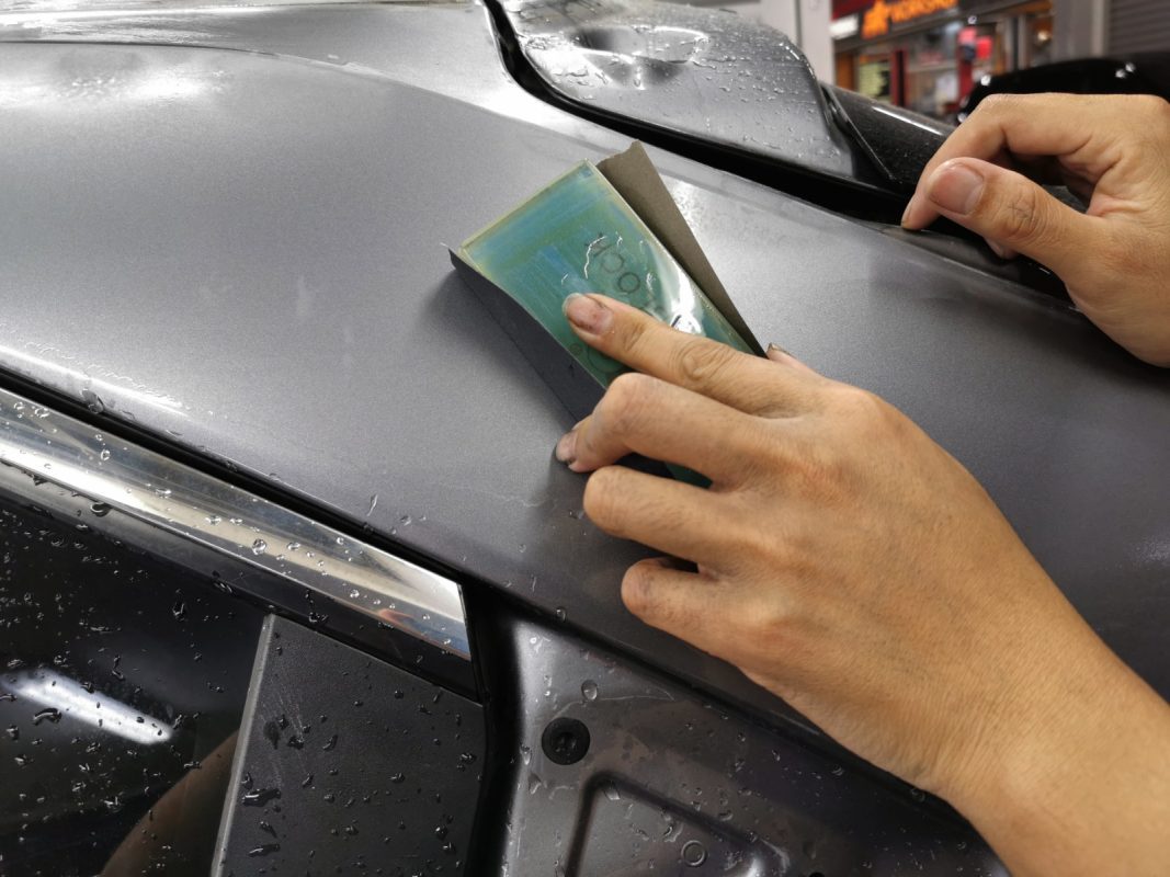 Wet-sanding the Eclipse Cross panels to level the surface before priming.
