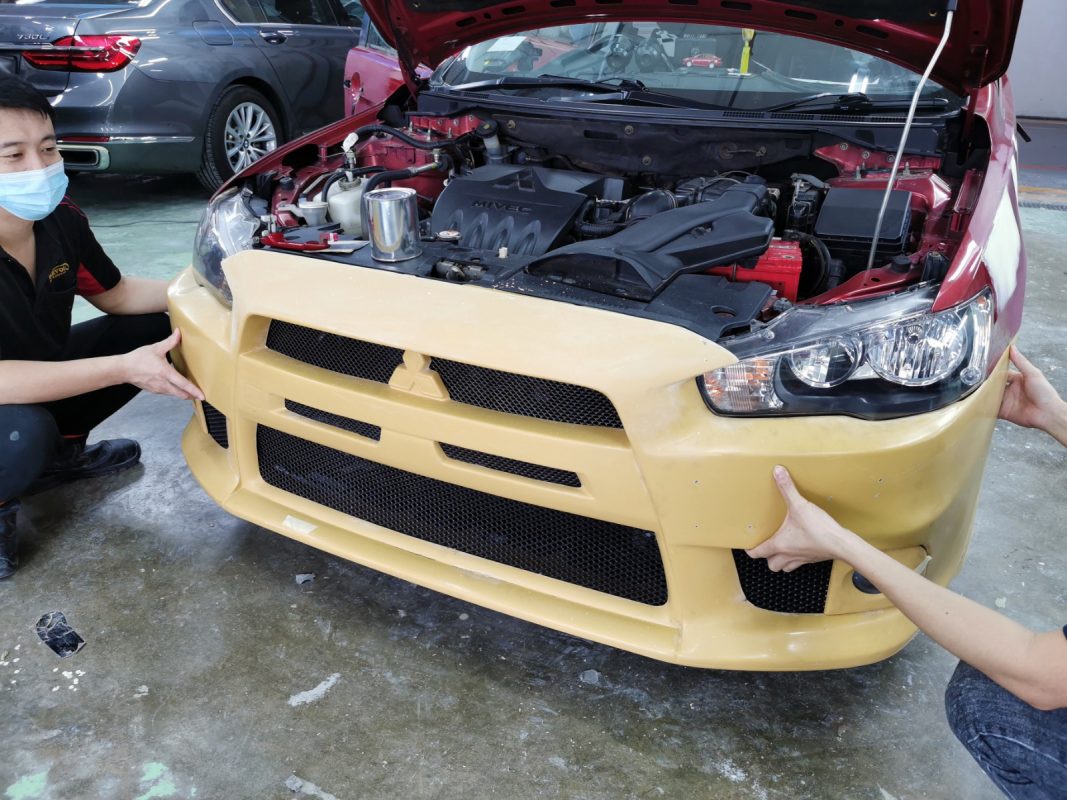 Bumpers and mirrors being dismantled from the Mitsubishi Lancer.