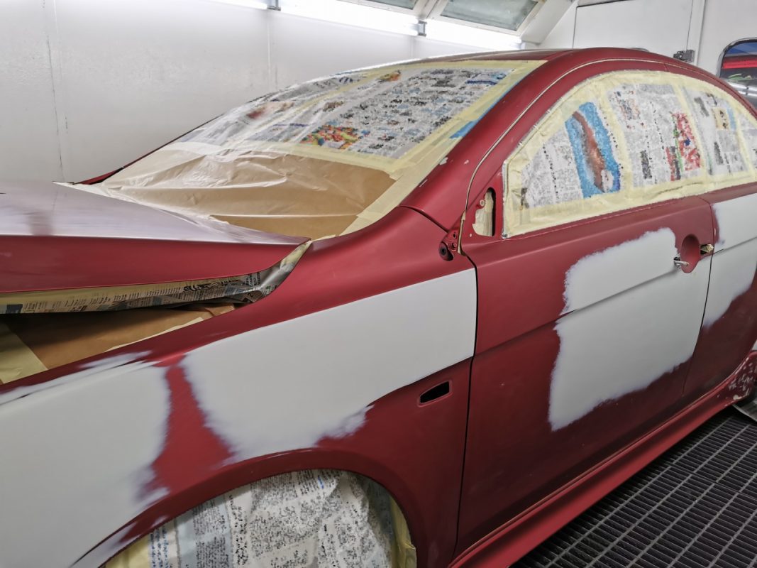 Non-painted surfaces being masked off on the Lancer before spraying.