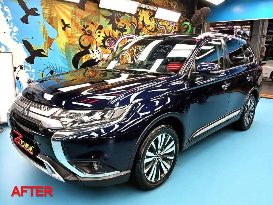 Dark blue Mitsubishi Outlander from the front three-quarter in the workshop after its full respray and coating.