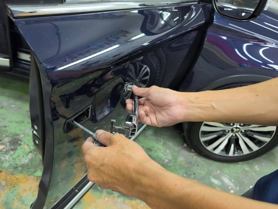 Hands unbolting a door fitting on the Outlander.