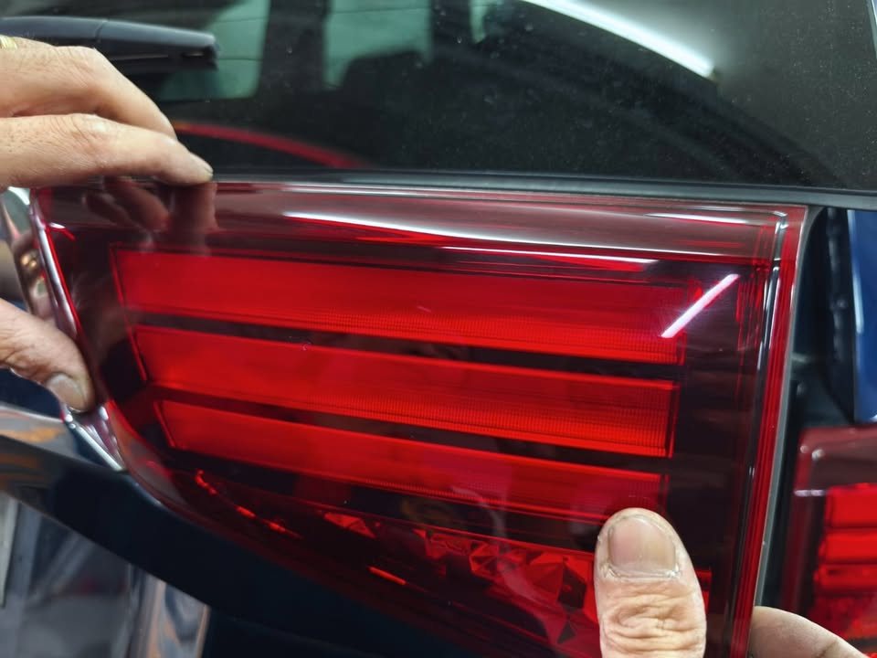 Hands removing a red tail lamp from the Outlander.