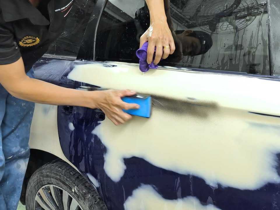 Team member sanding filler patches on the Outlander's side panels.