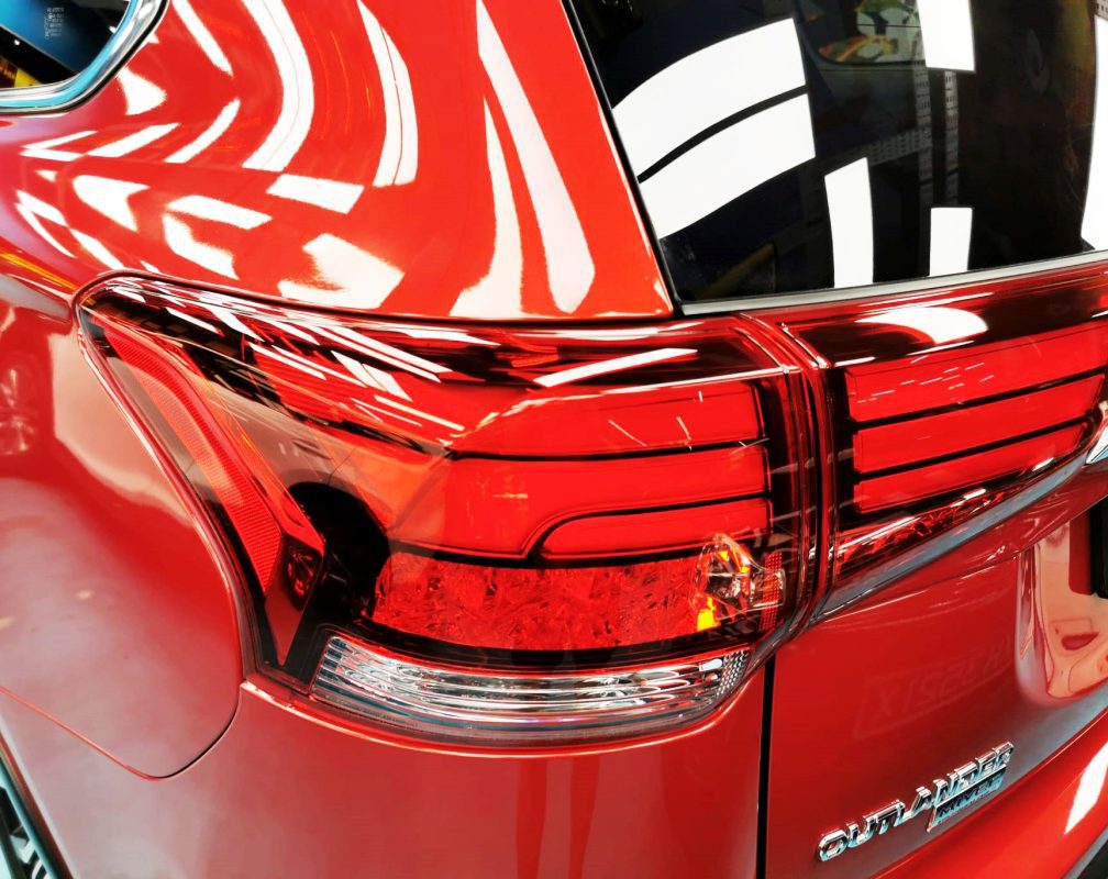 The coated bonnet of the Mitsubishi Outlander under workshop lighting.