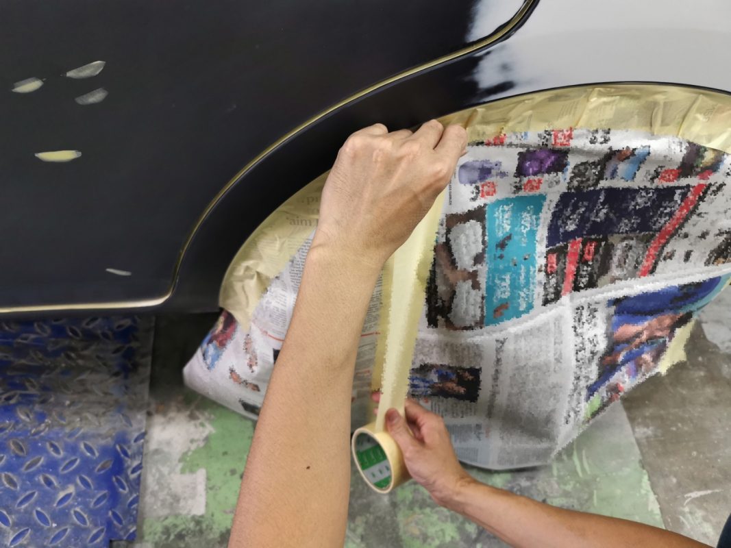 Spray painting in progress on the Nissan Almera inside the spray booth.