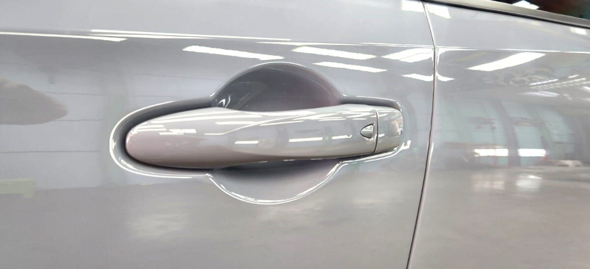 The coated bonnet of the Nissan Note under workshop lighting.
