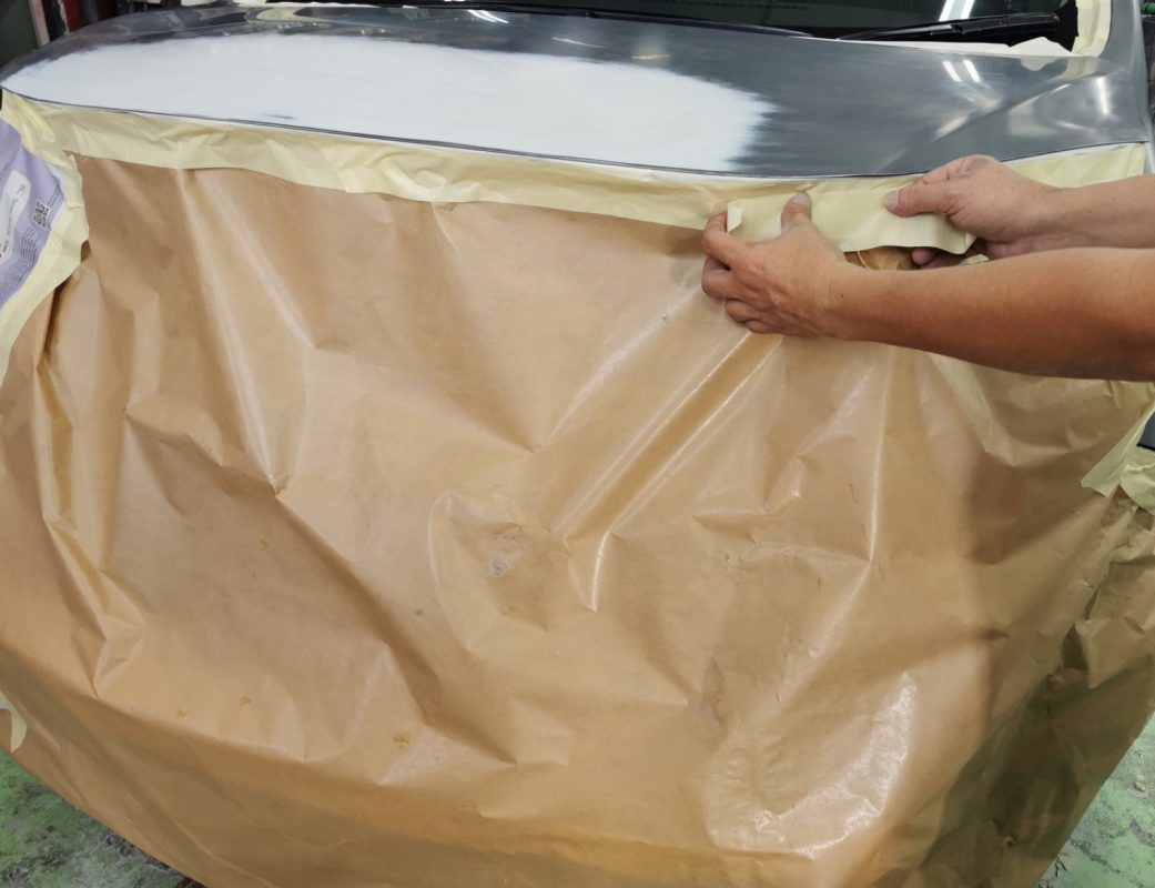 Non-painted surfaces being masked off on the Note before spraying.