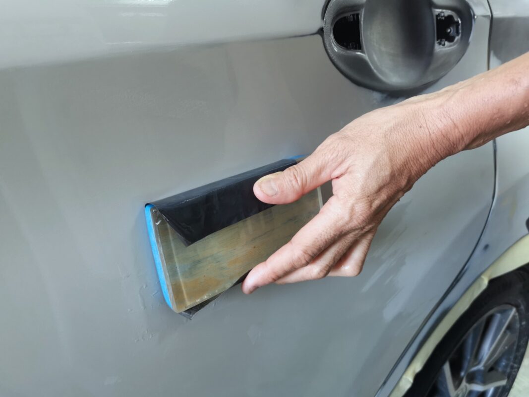 The Nissan Note masked with paper to protect non-painted surfaces before the spray booth.