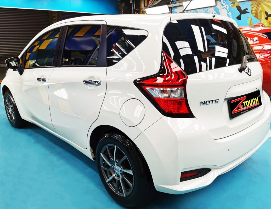 The coated bonnet of the Nissan Note under workshop lighting.