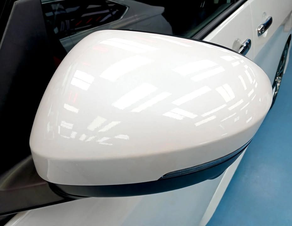 White side mirror cap reflecting the ceiling lights.