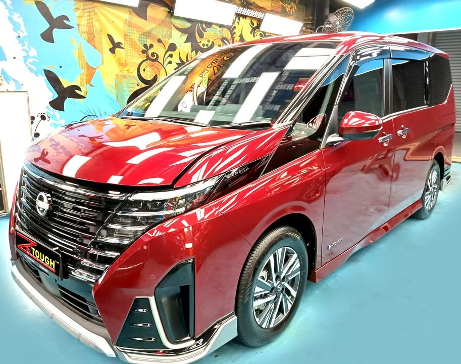 Red Nissan Serena MPV, front three-quarter view, in the Revol Carz workshop after coating.