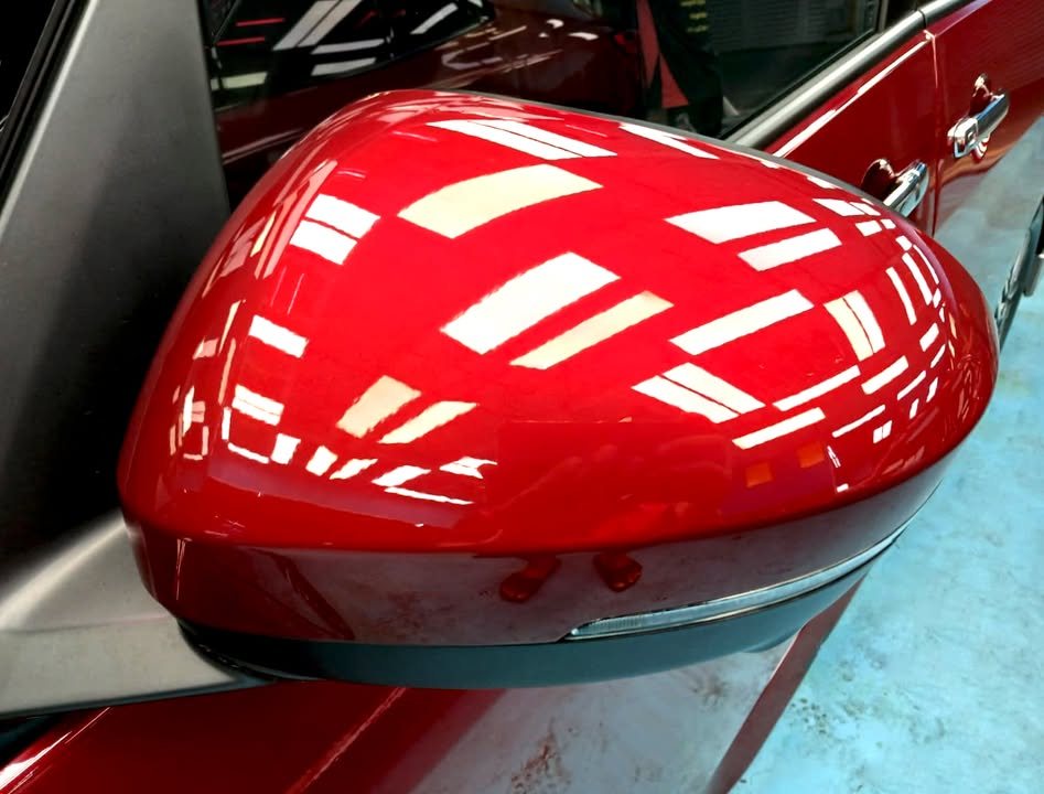 Red wing mirror on the Nissan Serena reflecting the workshop lights.