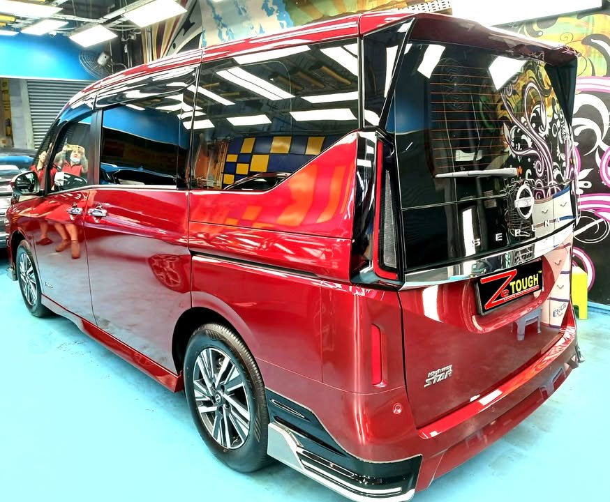 Red Nissan Serena, rear three-quarter view, in the workshop.